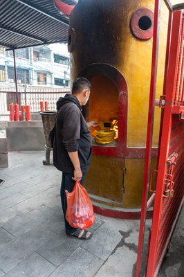 Man burning Joss Paper (Sheets of silvered paper.), Jakarta Chinatown, Indonesia 2022 - Java